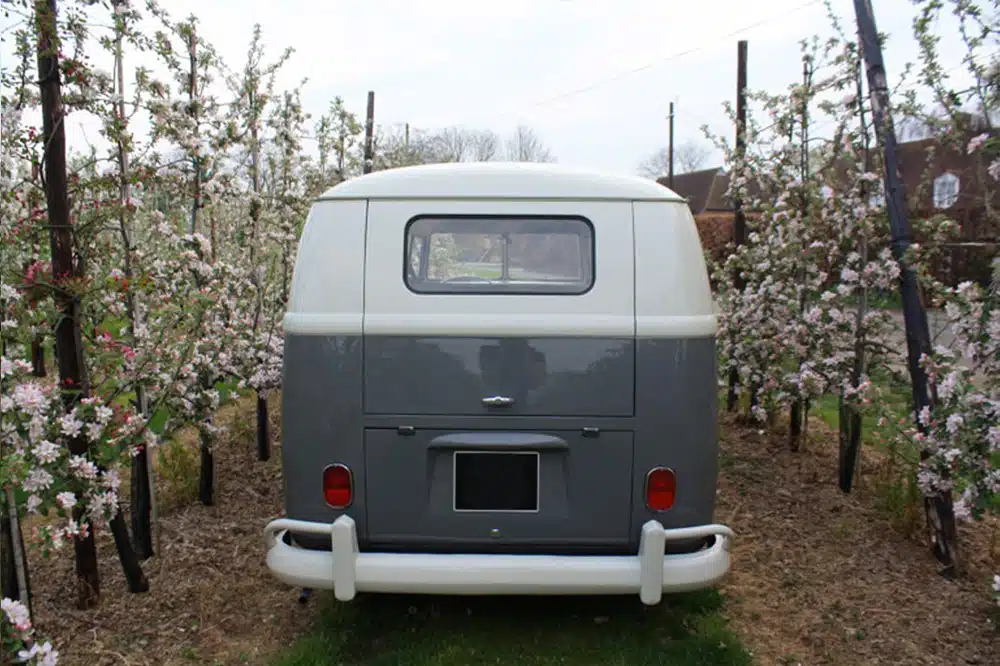 Een romantisch Volkswagen-busje als trouwauto, omringd door bloeiende fruitbomen in een pittoreske boomgaard