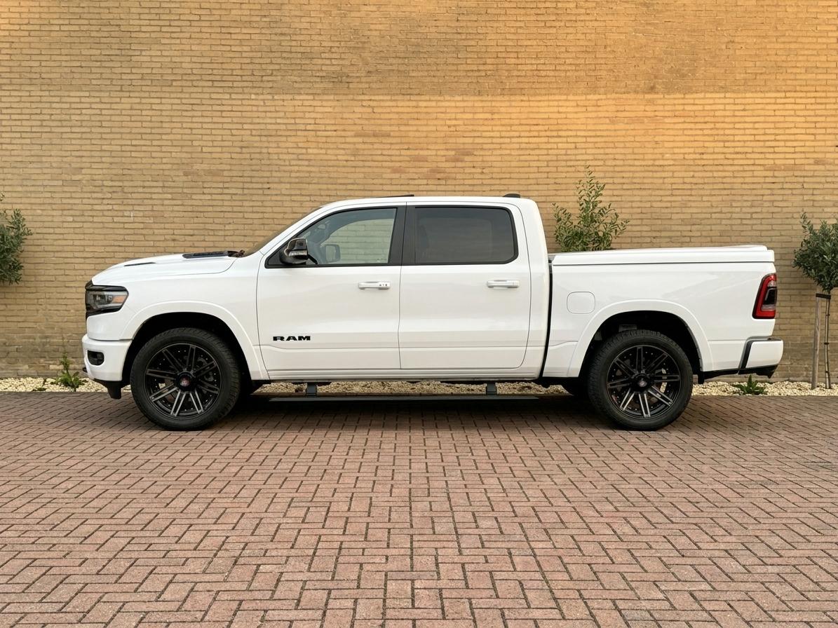 Zijaanzicht van een witte Dodge RAM pick-up met dubbele cabine en zwarte velgen als trouwauto